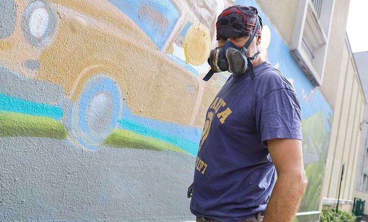 L'artiste JACE - le mur Orléans L'artiste Jace en tenue de peintre devant le mur rue Henri Roy à Orléans